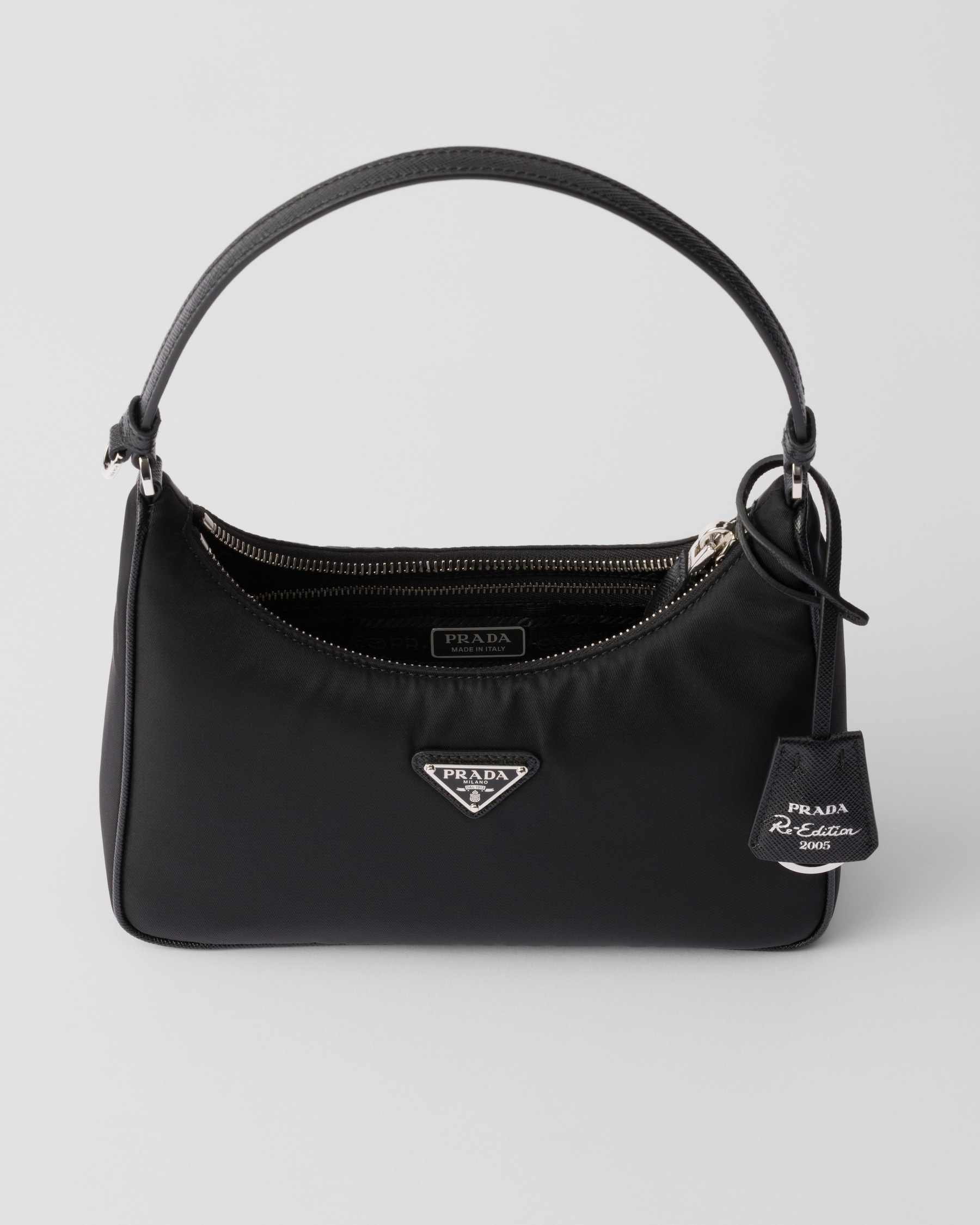 Black zip-top bag with triangle badge, short handle and Re-Edition tag; exact material unverified